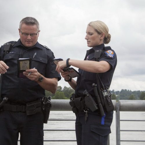 Two police officers compare notebooks as they stand in Westminster Pier Park.