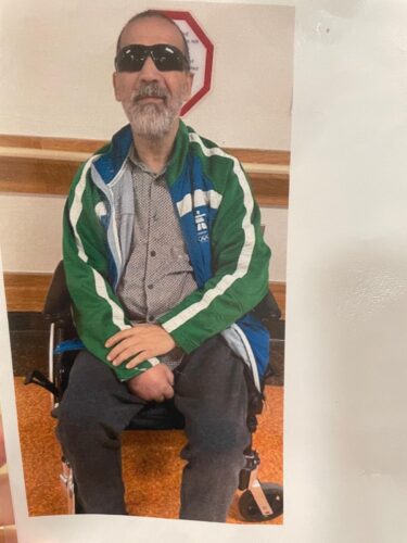 Noureddine wears sunglasses and is seated in his wheelchair.
