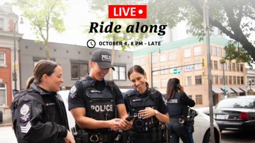 Officers smile while looking at a phone.