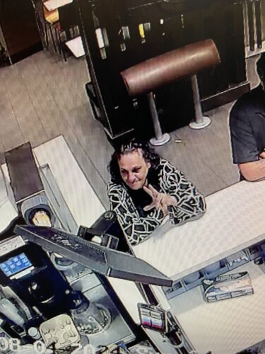 A suspect in an assault investigation. The female has brown hair and a black and white top.