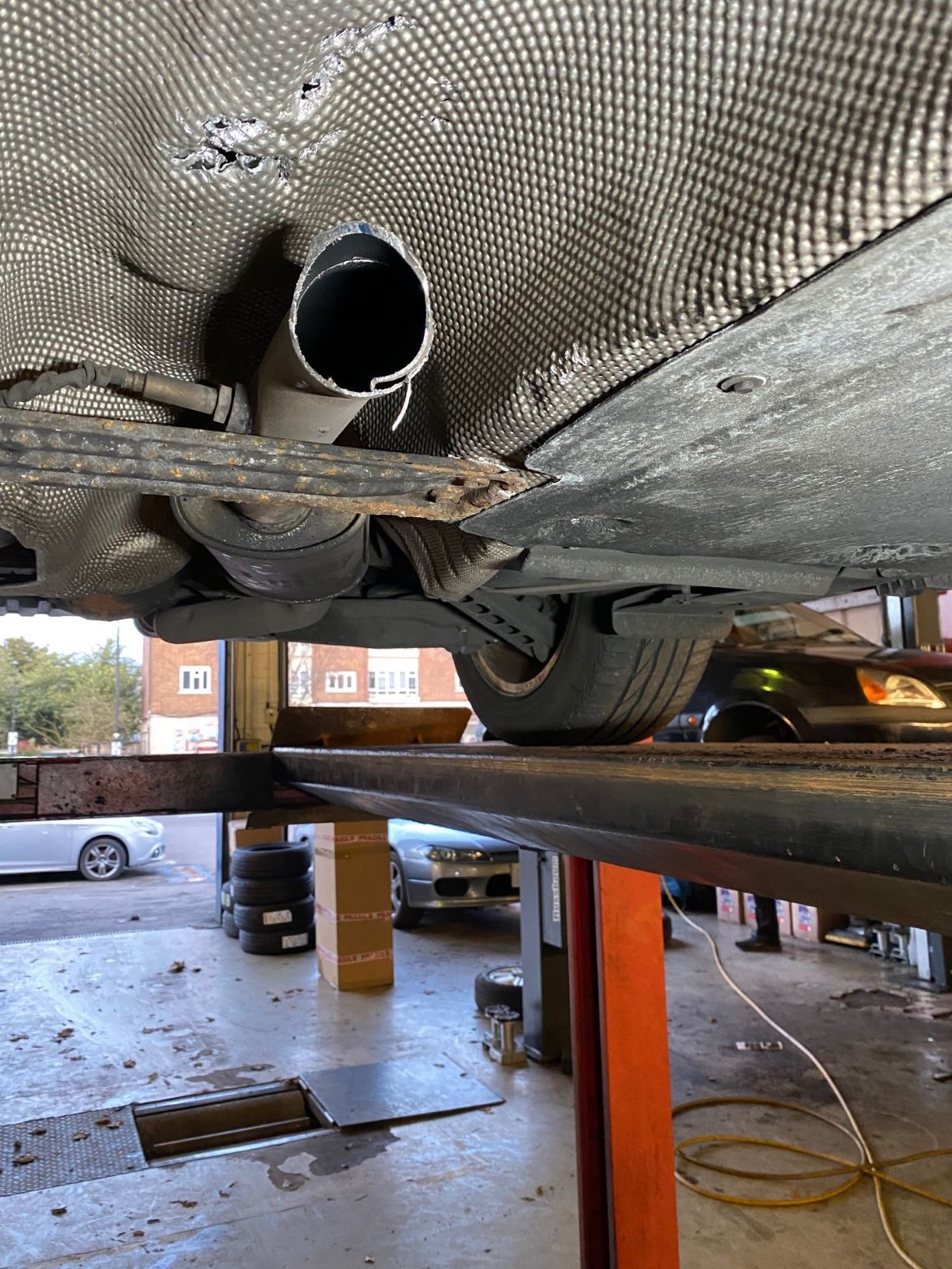 A car on a hoist has had its catalytic converter cut out.